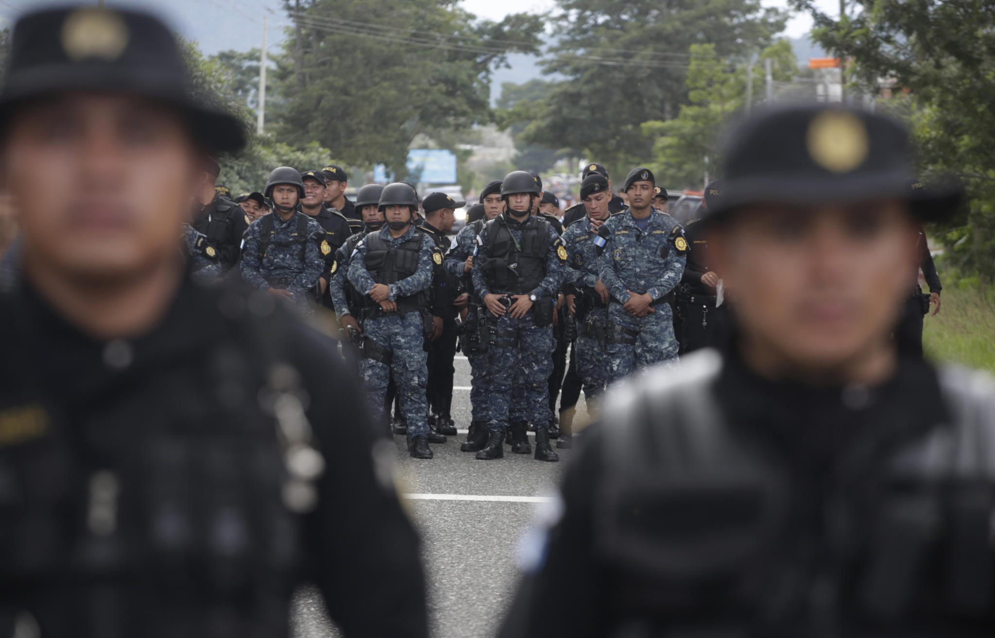 Guatemalan police stand in the road to block Honduran migrants making their way to the U.S., in Esquipulas, Guatemala, Monday, Oct. 15, 2018. The caravan began as about 160 people who first gathered early Friday to depart from San Pedro Sula, Honduras, figuring that traveling as a group would make them less vulnerable to robbery, assault and other dangers common on the migratory path through Central America and Mexico. The group has since grown to at least 1,600 people. (AP Photo/Moises Castillo)