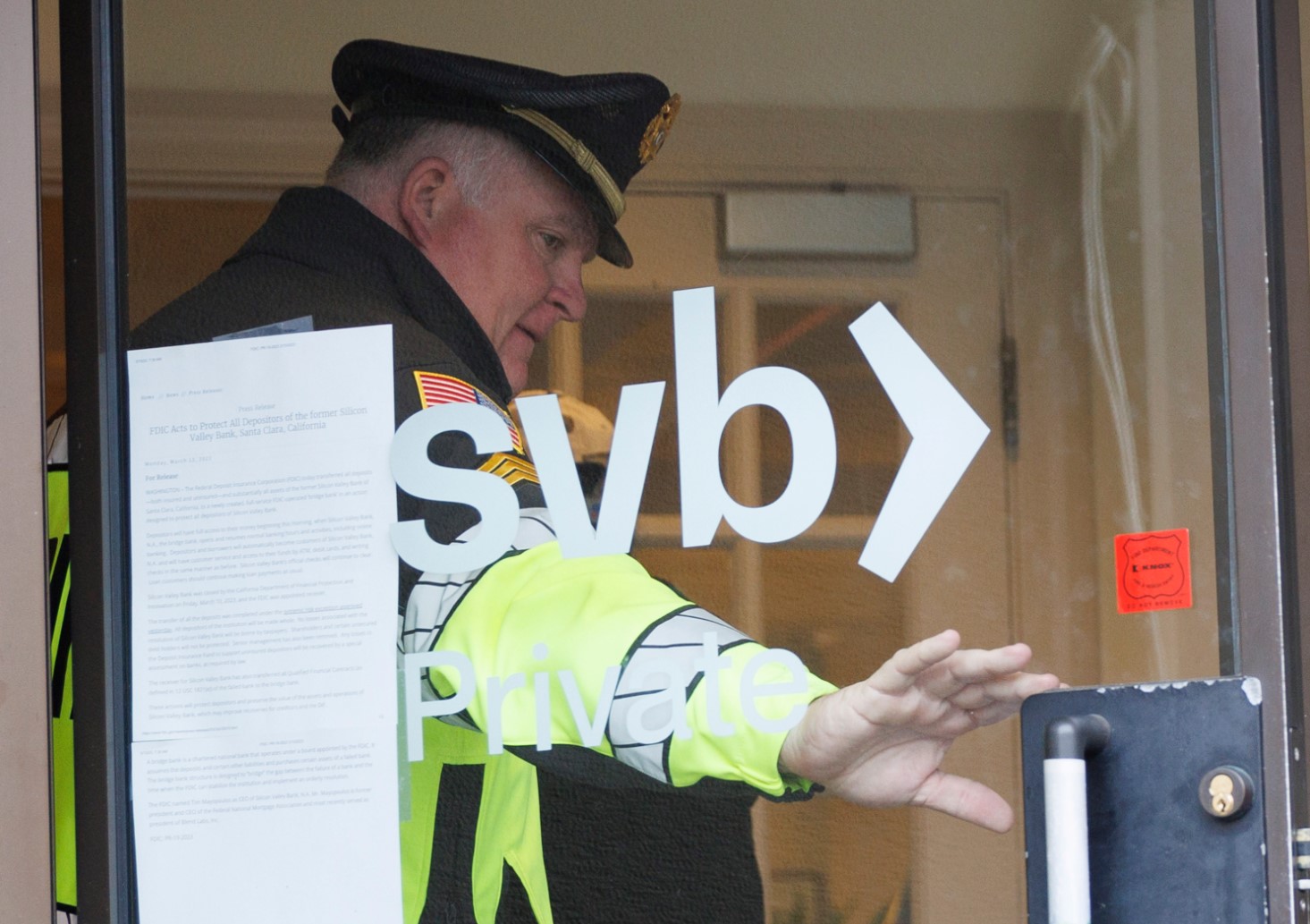 Полицай държи вратата пред клиент в клон от фалиралата банка
